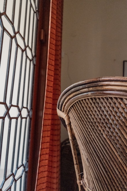 a close up of a wicker chair near a brick wall
