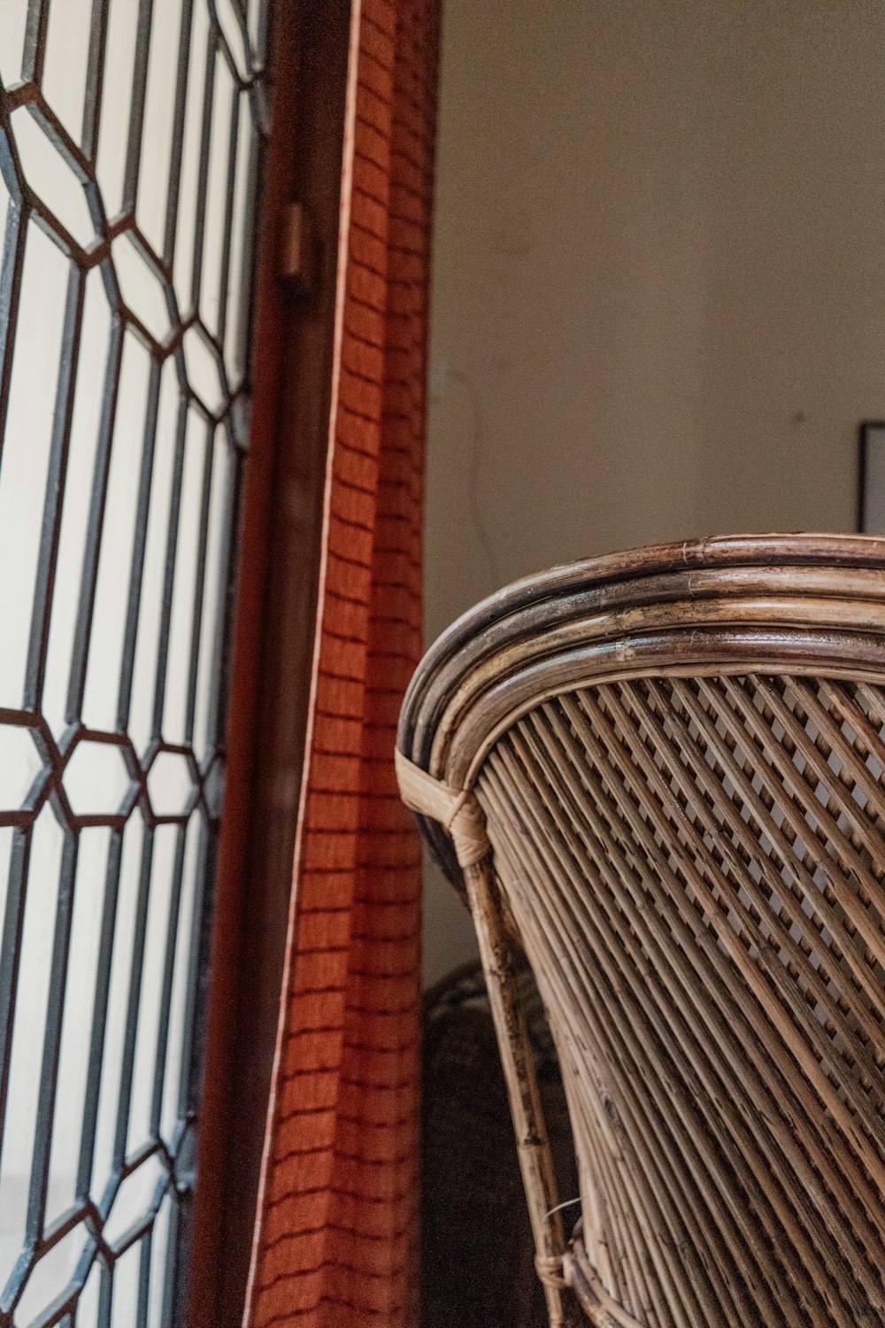 a close up of a wicker chair near a brick wall