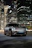 A sleek 2023 Volvo S90 parked curbside with city skyscrapers in the background at sunset.