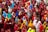 A large crowd of women dressed in brightly colored hijabs gather closely together. The hijabs are in various shades including red, blue, green, yellow, and orange. Some women are holding papers, and others appear to be interacting with each other.