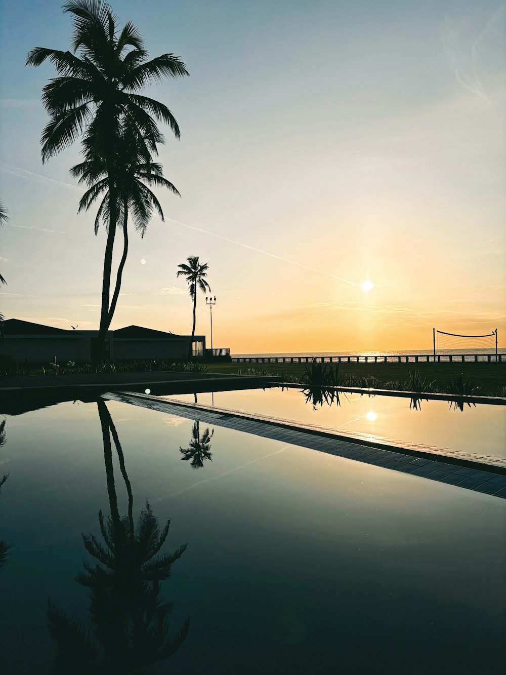 the sun is setting over a swimming pool