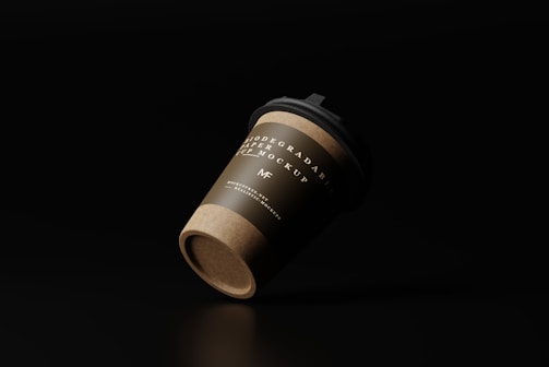 A biodegradable paper cup with a lid is positioned against a dark background, showcasing a label with elegant typography.