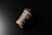 A disposable paper coffee cup with a black lid rests against a dark background. The cup has an earthy brown band with white text indicating it is a biodegradable paper cup mockup. The lighting casts a smooth gradient, creating shadows and highlights on the cup, giving it a realistic appearance.