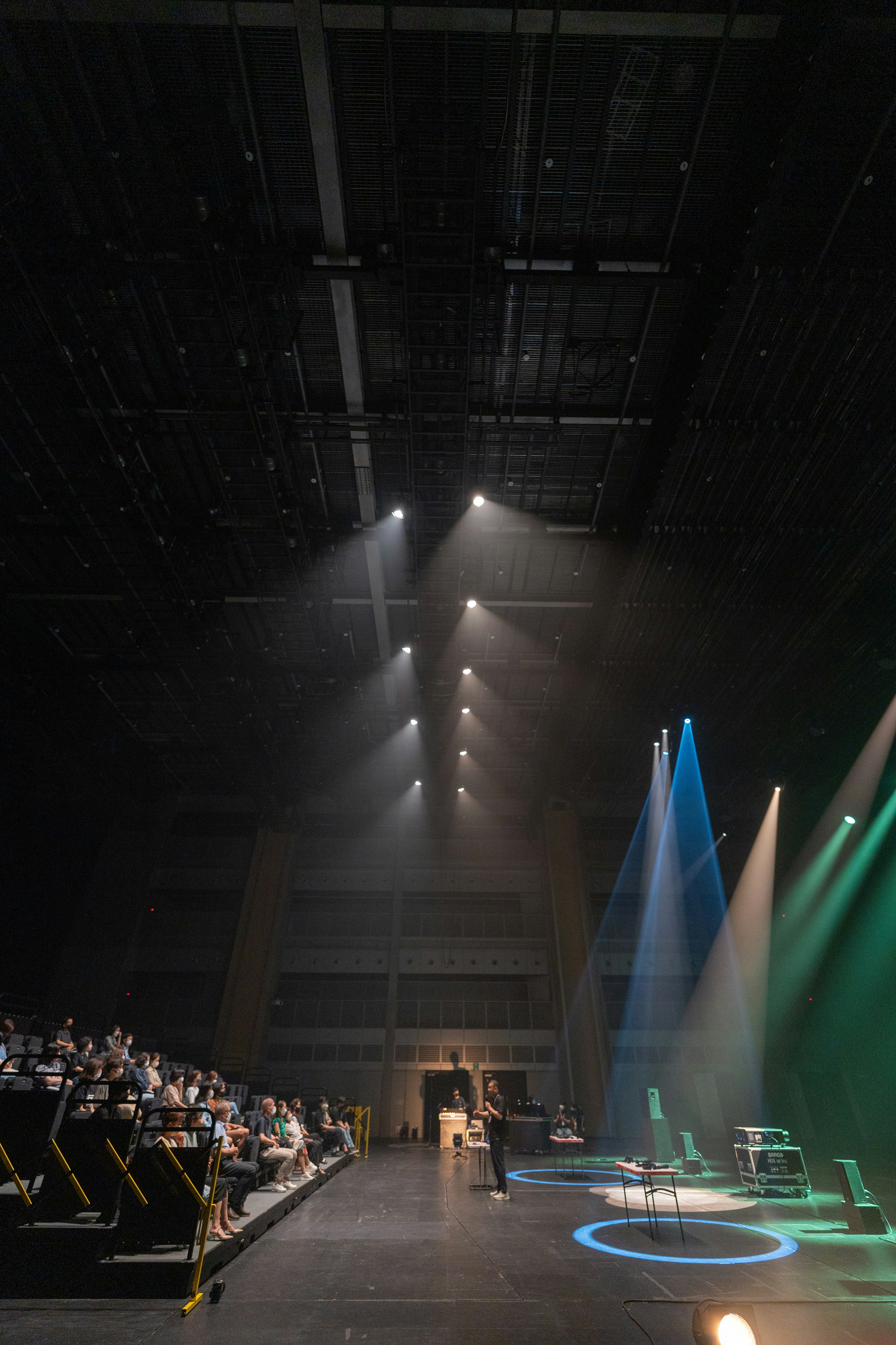 A professional stage curtain being installed in a large auditorium with bright lighting.