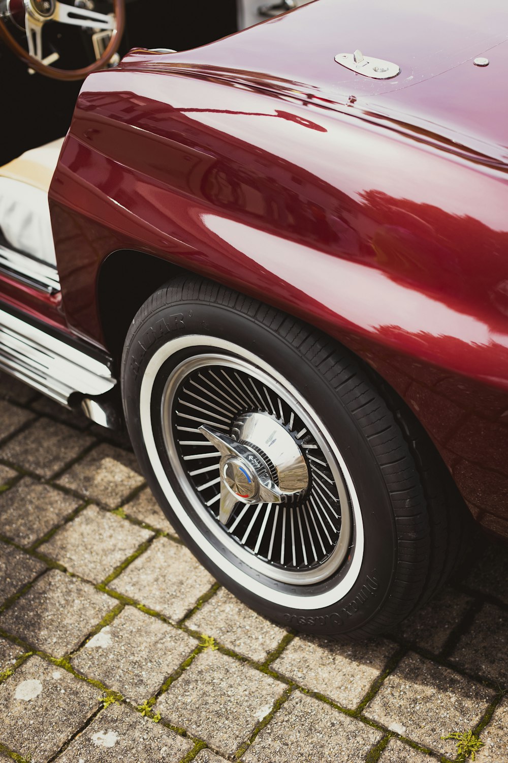 a close up of a red car parked on a brick road