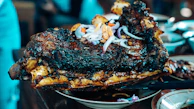 Grilled meat dish served on a stone plate with warm lighting highlighting its texture.