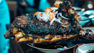 Grilled meat dish served on a stone plate with warm lighting highlighting its texture.