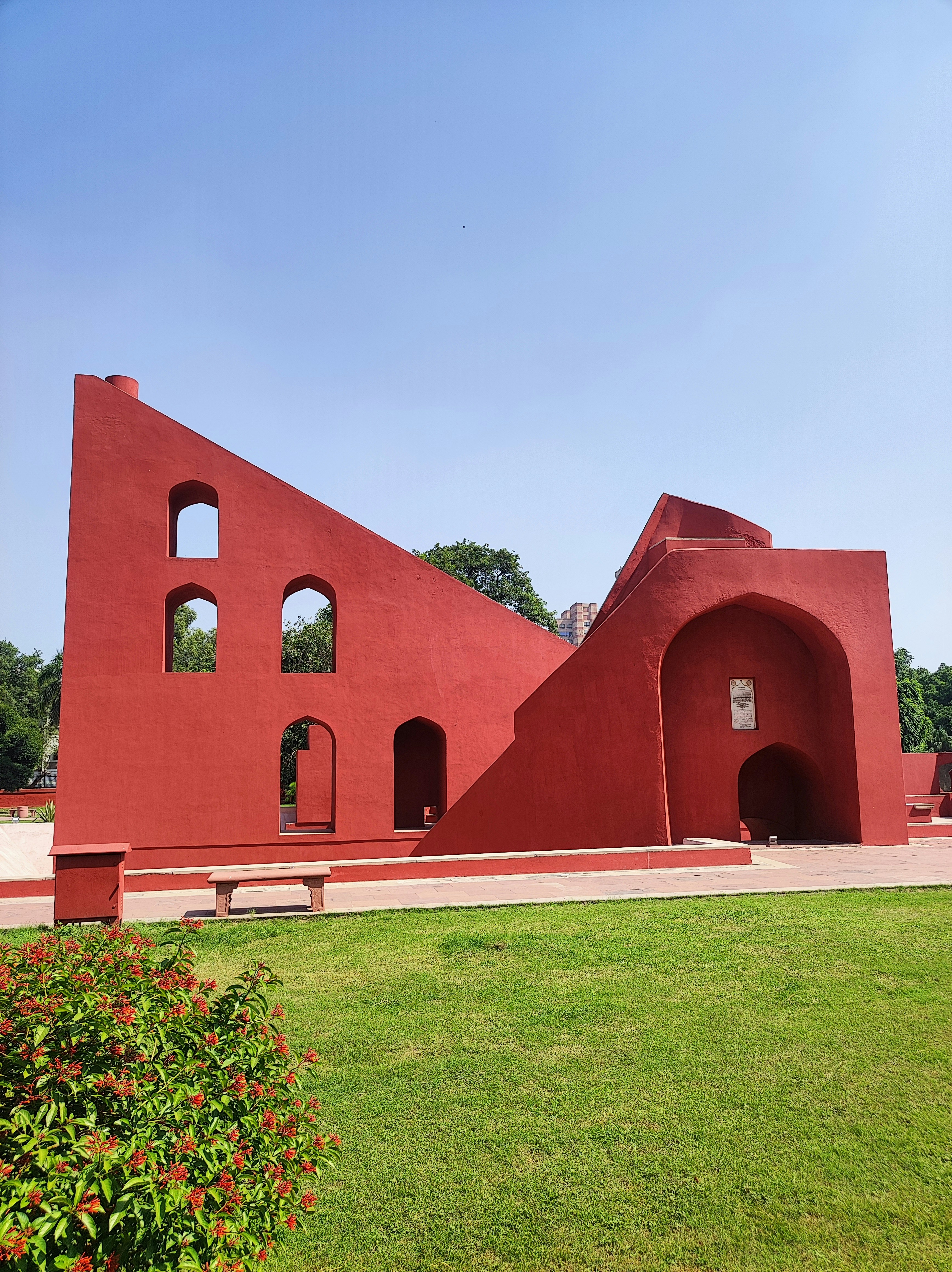 um grande edifício vermelho com janelas arqueadas em um parque