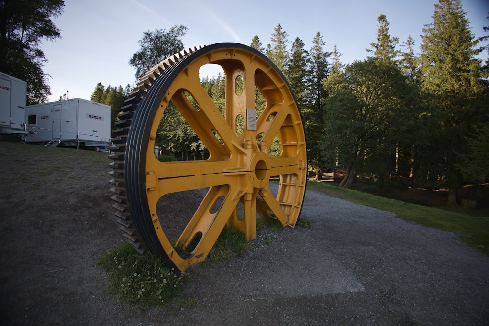 a large yellow wheel sitting on top of a grass covered field