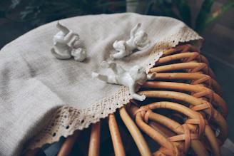 Close-up of delicate porcelain figurines displayed on a lace-covered table at a tag sale.