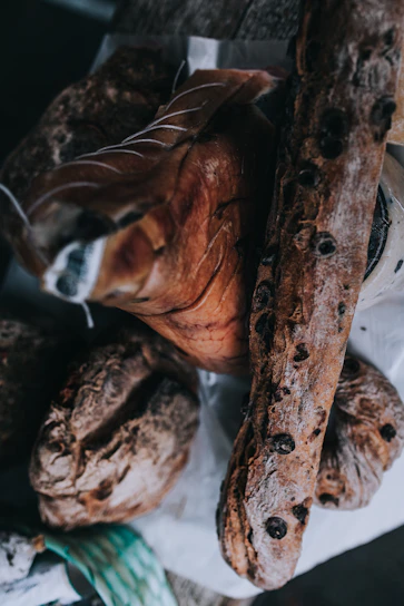 Rustic wooden basket filled with fresh artisanal cheeses and cured meats on a farmhouse table.