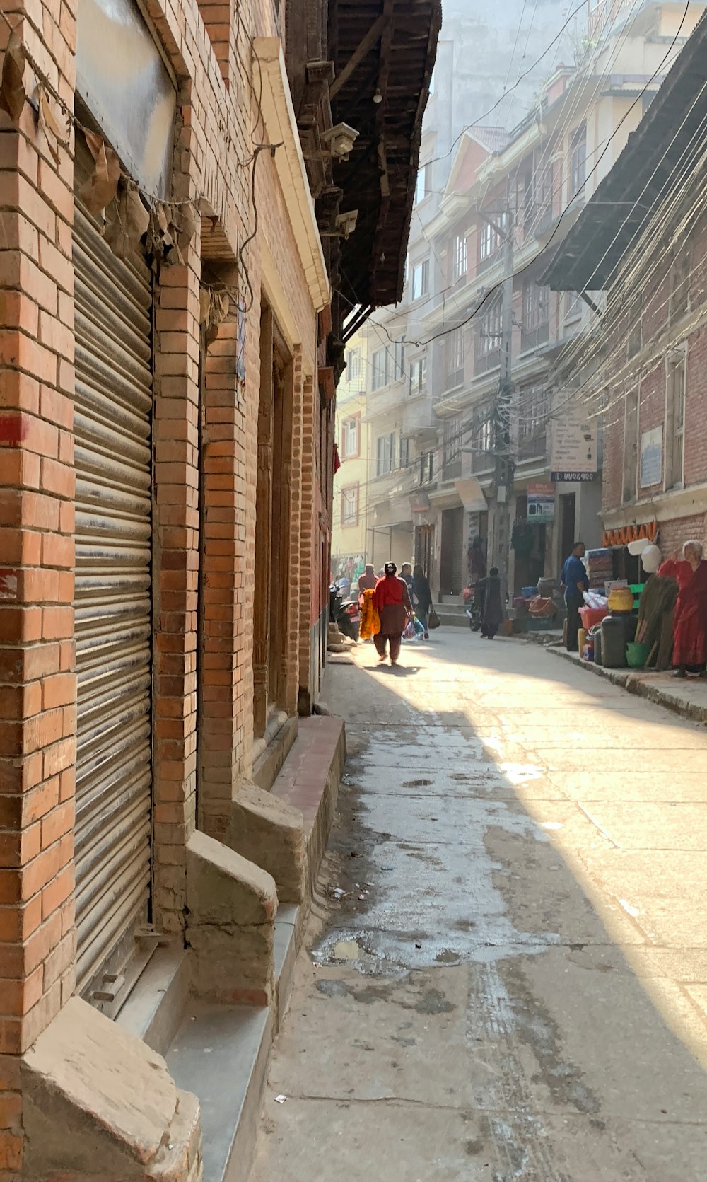 a woman walking down a street next to a brick building