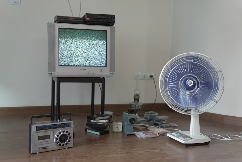 a television sitting on top of a wooden floor next to a fan