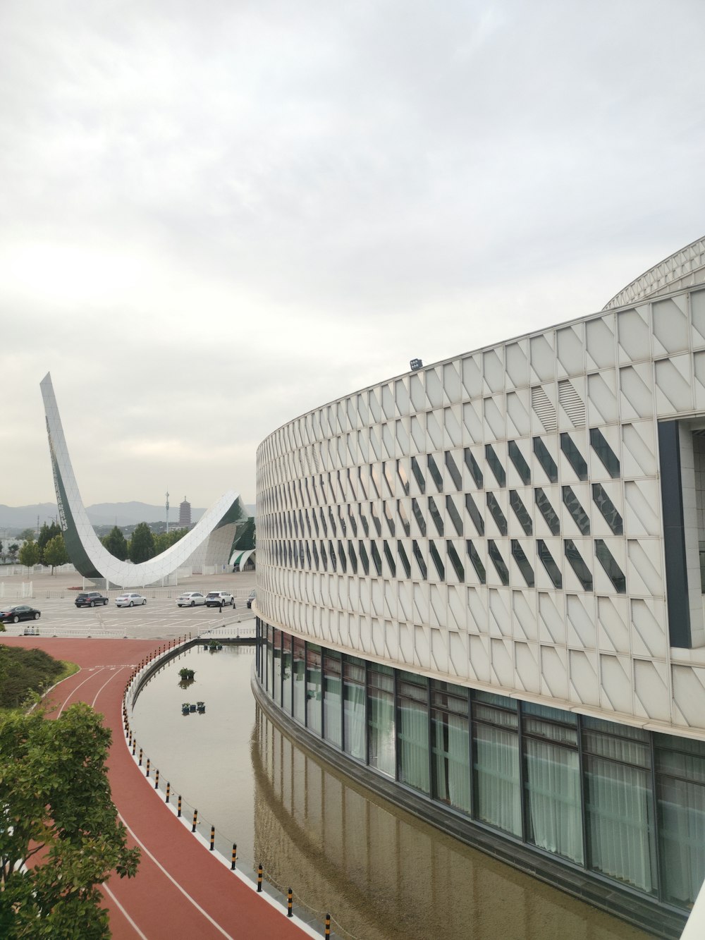 a large building with a curved roof next to a body of water