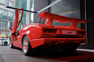 A striking red sports car parked inside the modern industrial luxury atelier.