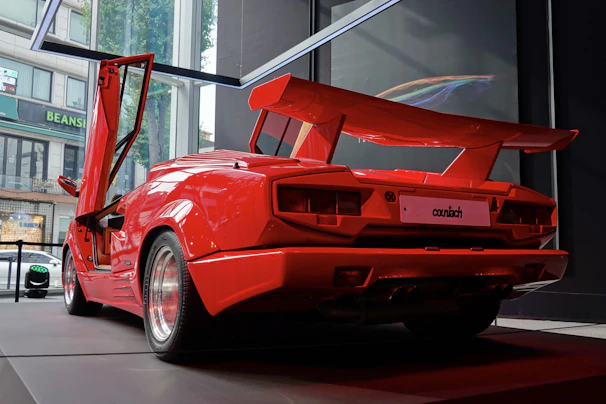 A striking red sports car parked inside the modern industrial luxury atelier.