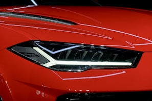 A close-up of a custom red-accented futuristic headlight with sleek black housing