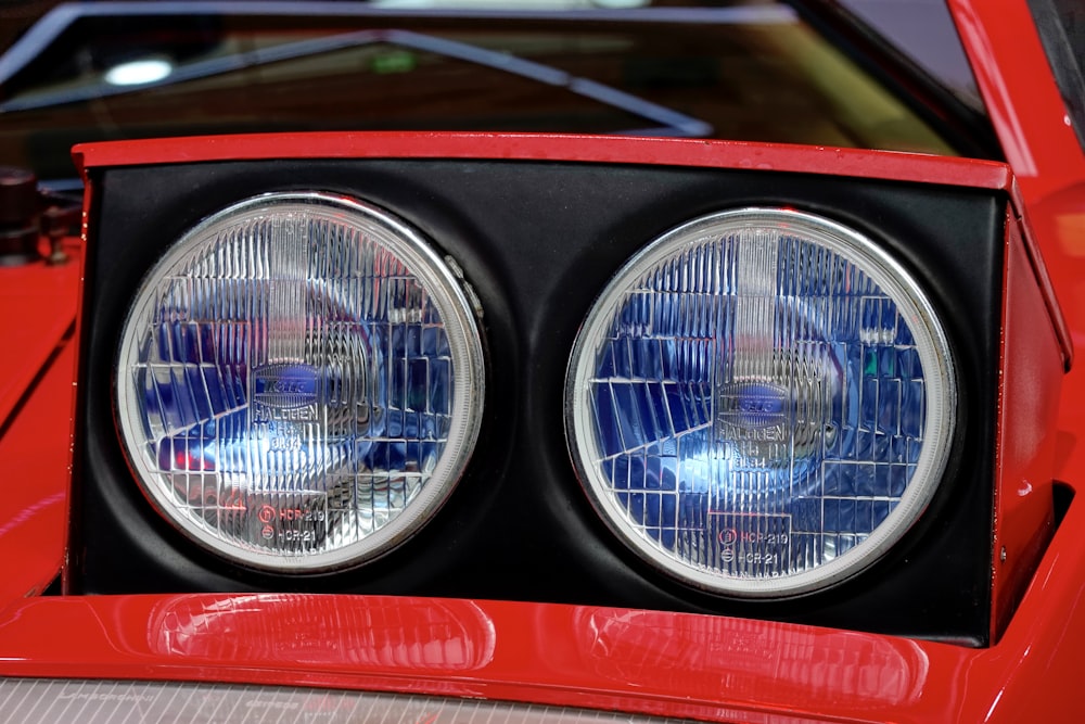 a close up of two headlights on a red sports car