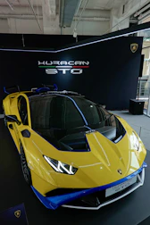 A Lamborghini Huracán STO parked overlooking a stunning mountain vista during sunset.