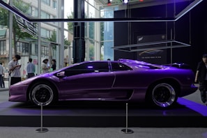 Front view of a sleek purple car with yellow accents parked in a modern showroom