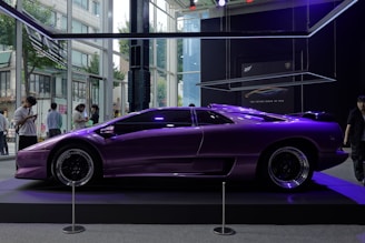 Front view of a sleek purple car with yellow accents parked in a modern showroom