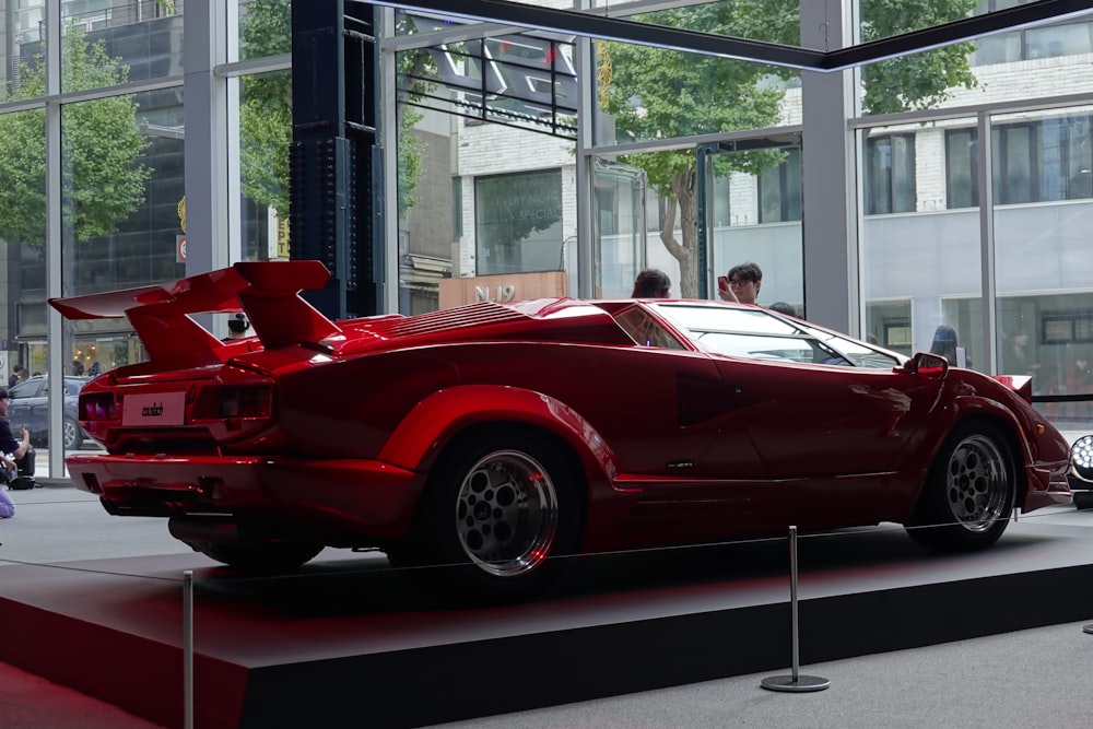 a red sports car on display in front of a building
