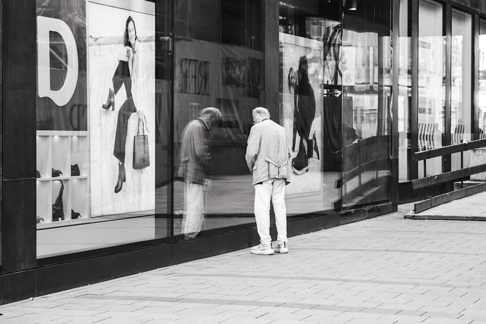 a couple of men standing in front of a store window