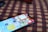 A smartphone with a vivid display showing various app icons lies on a surface with a checkered pattern in red and black. The phone is positioned at an angle, partially in focus.