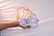A hand holding a stack of 100 Indian rupee banknotes. More stacks of similar banknotes are arranged in a fan-like pattern on a neutral background. The banknotes prominently feature a portrait of a notable figure.