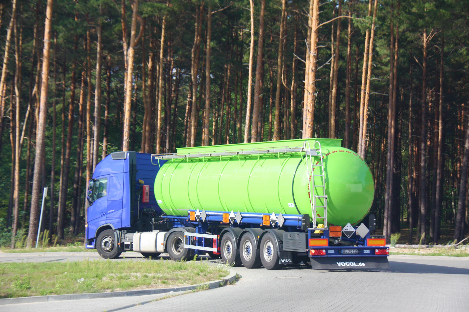 A green tanker truck traveling along a road