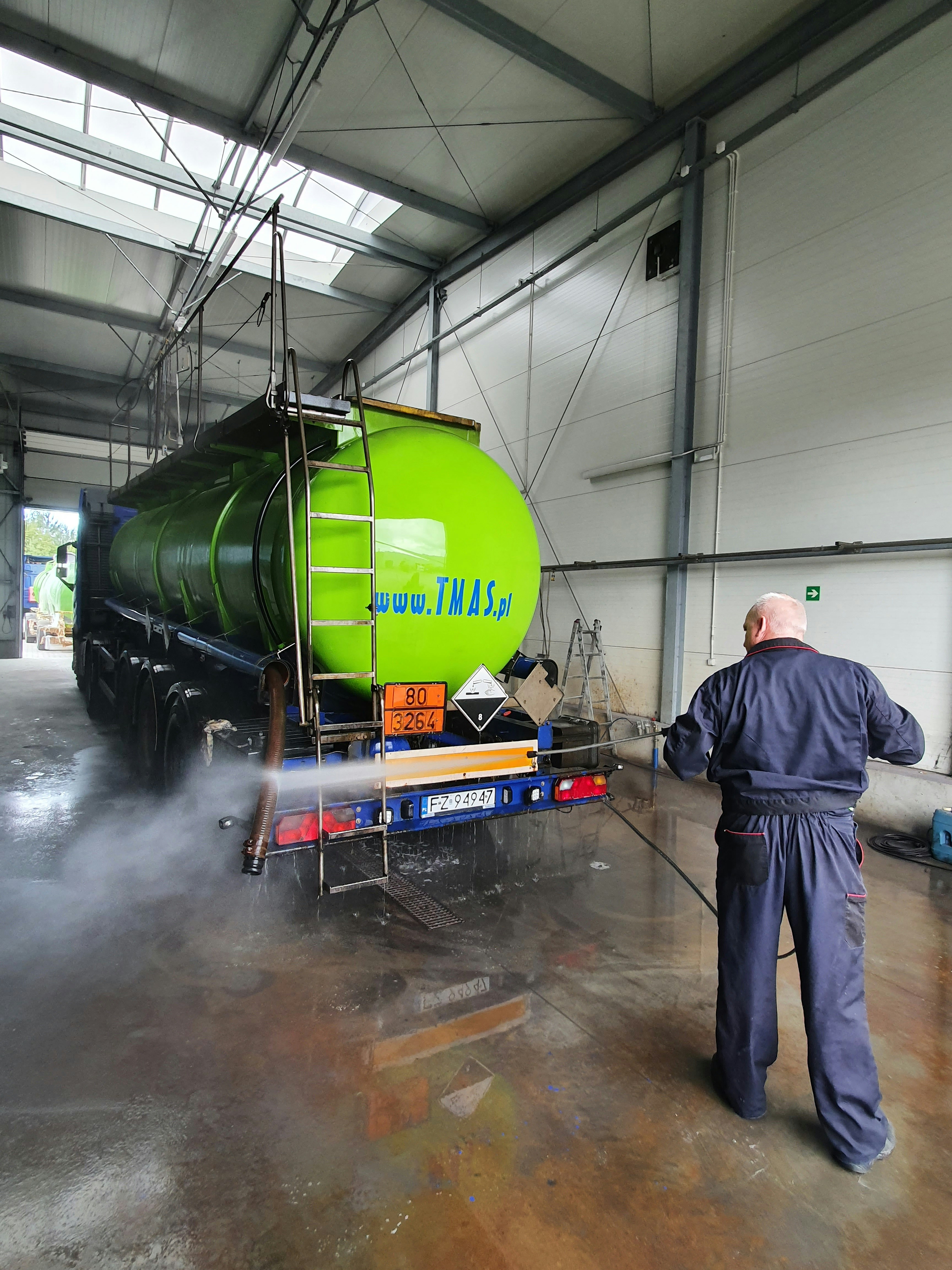 Worker washing the wheels and lower exterior of a heavy-duty truck