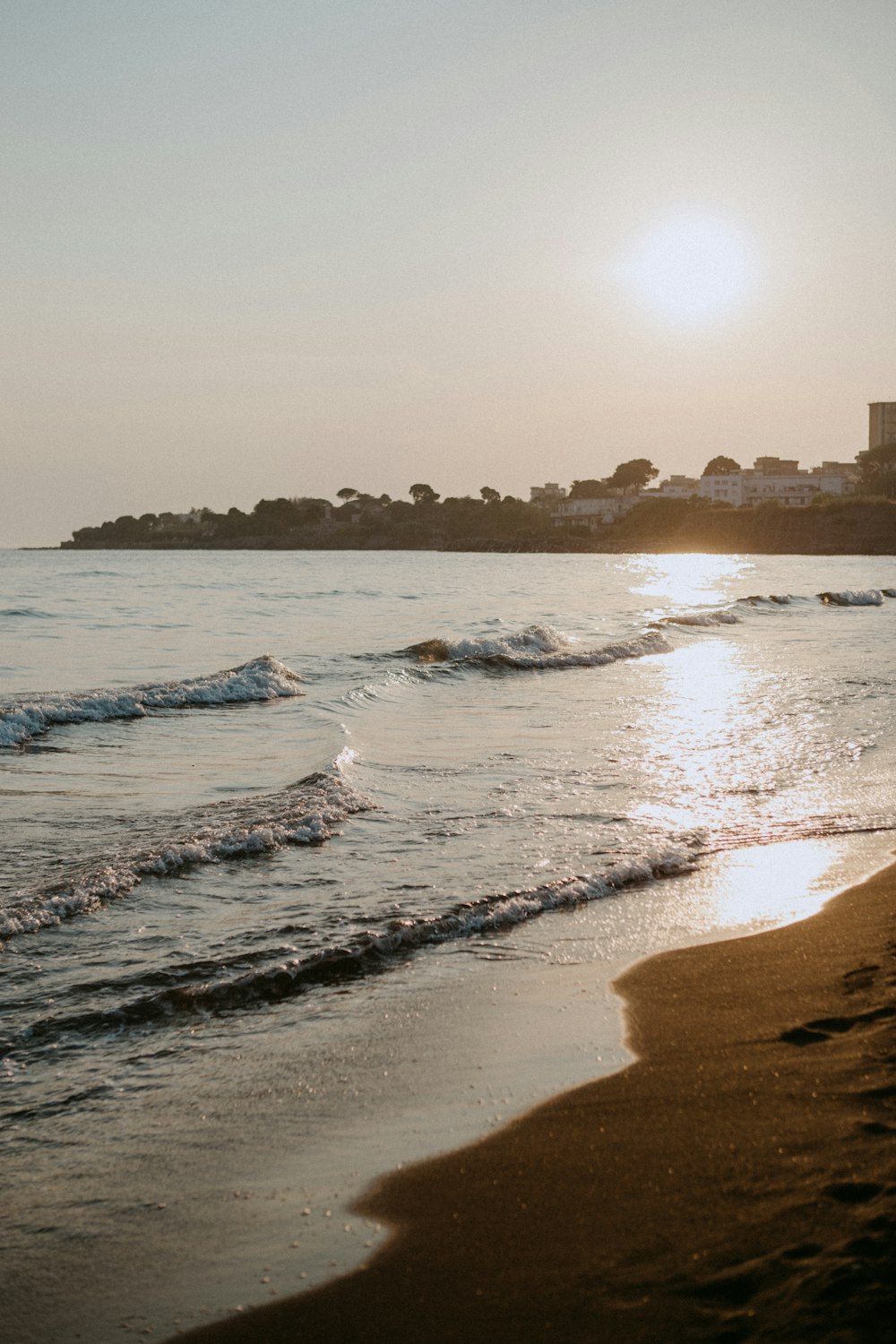 the sun is setting over the water at the beach