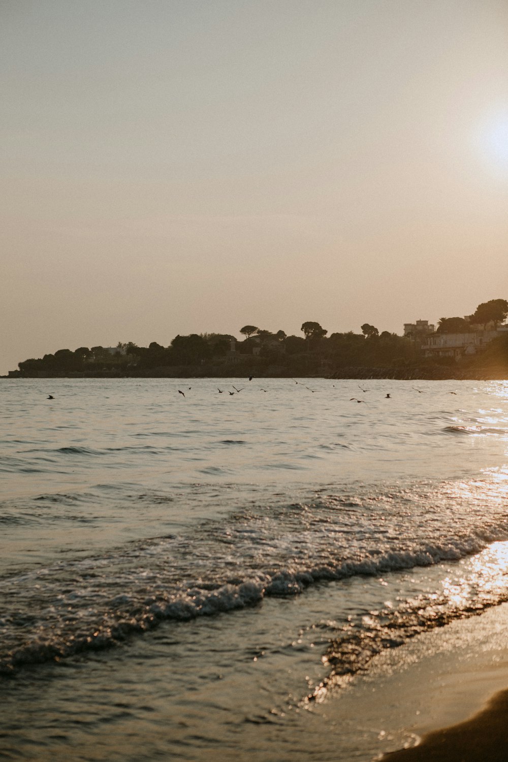 the sun is setting over the water at the beach