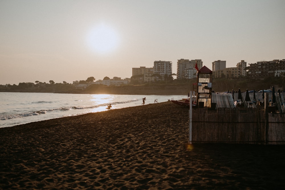 the sun is setting on the beach with a life guard tower