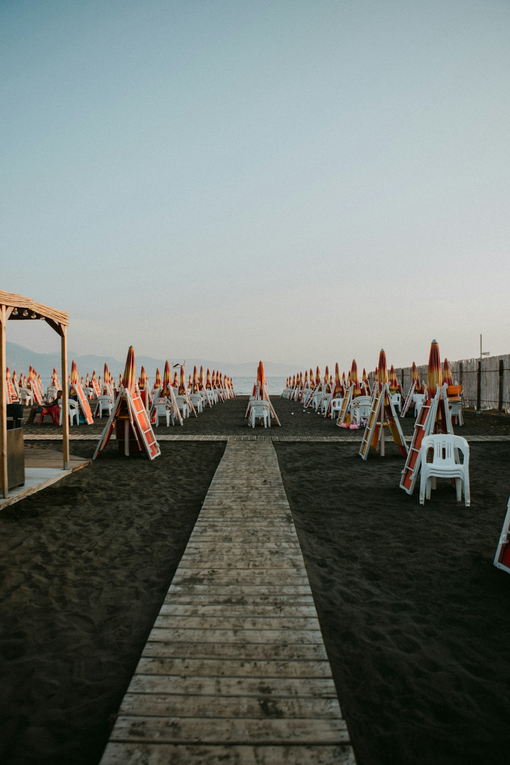 a wooden walkway leading to a beach covered in lawn chairs