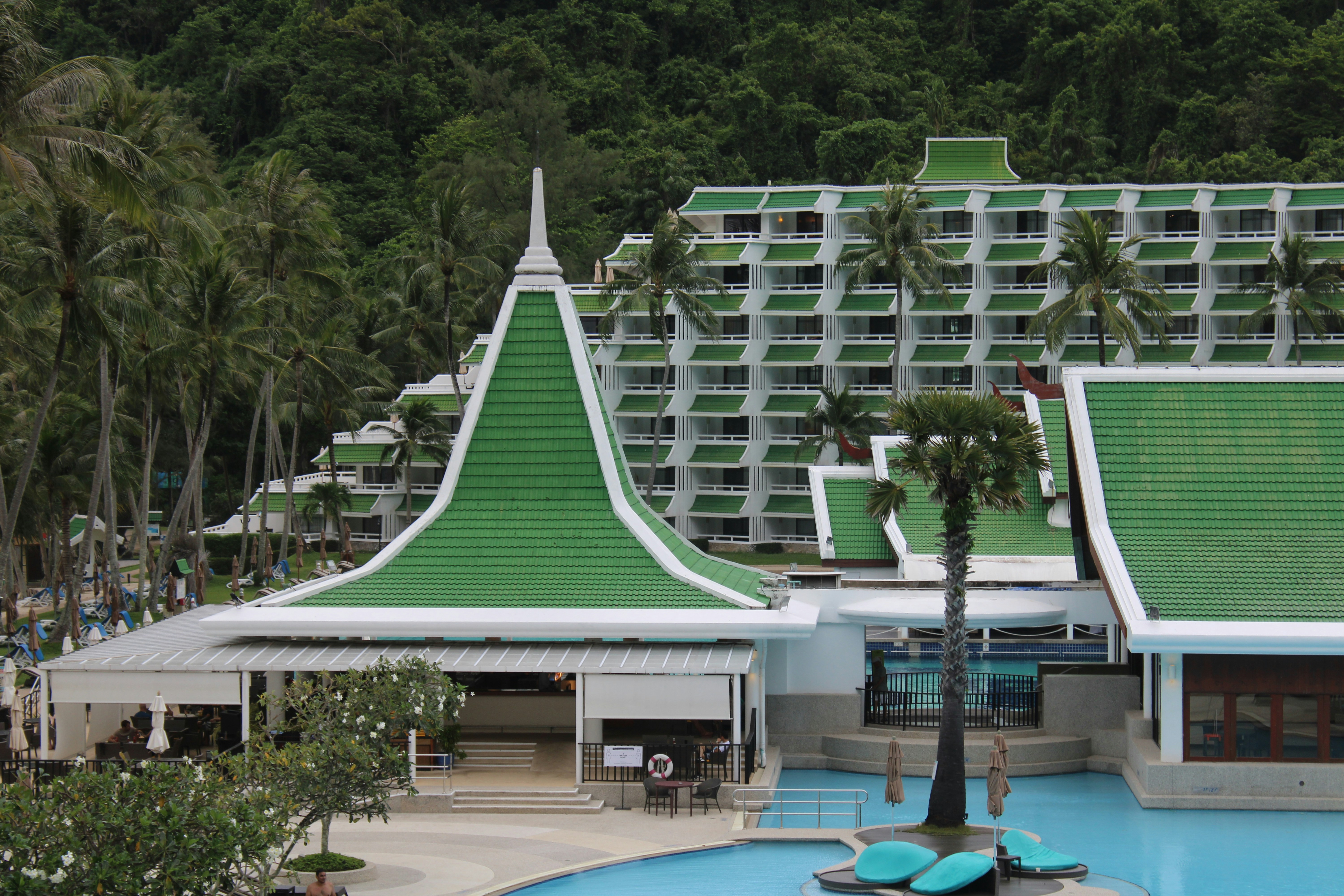 a large building with a green roof next to a pool, 