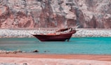 A traditional wooden boat gently sailing along the calm Adriatic coast near Montenegro’s rugged shoreline.
