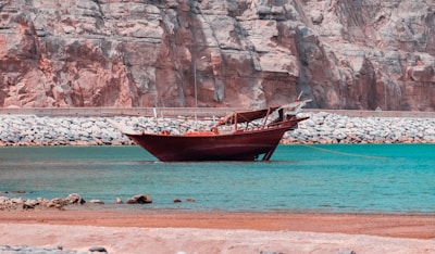 A traditional wooden boat gently sailing along the calm Adriatic coast near Montenegro’s rugged shoreline.