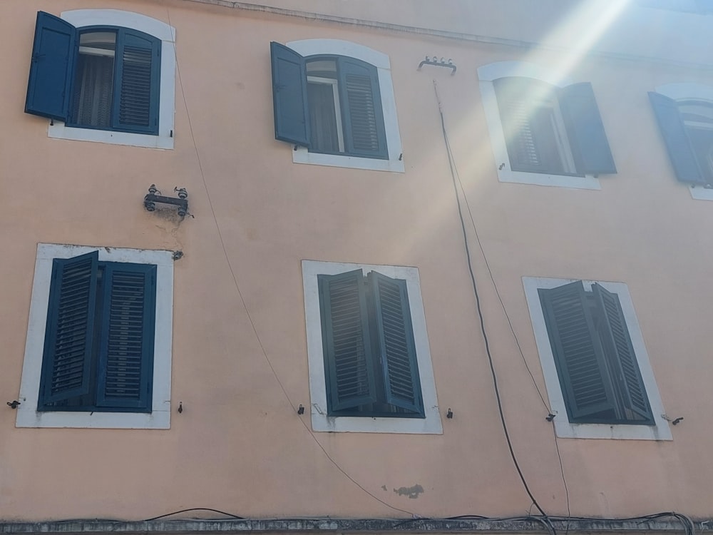 un edificio rosa con persianas azules y un reloj