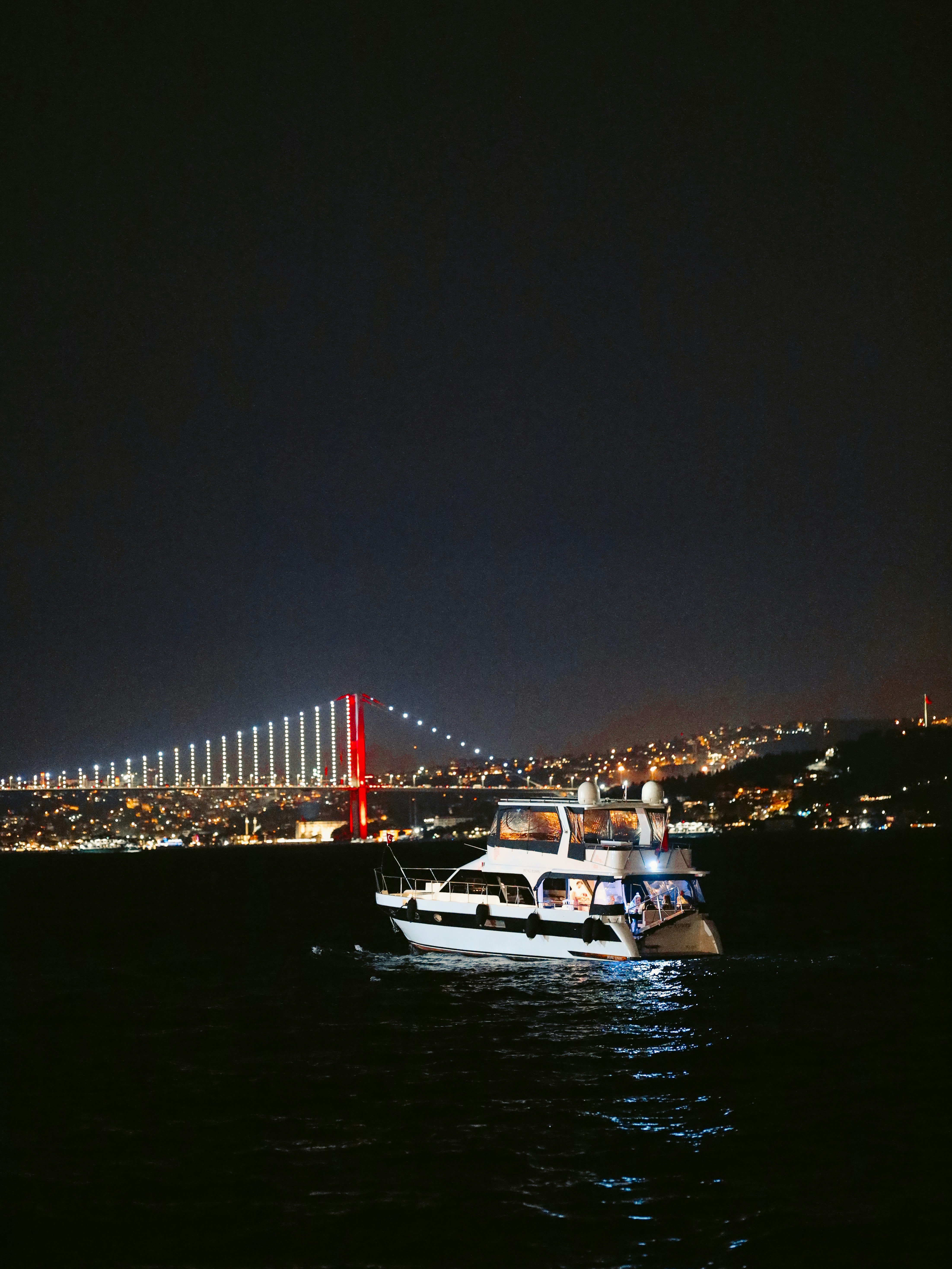 a boat in the water at night with a bridge in the background