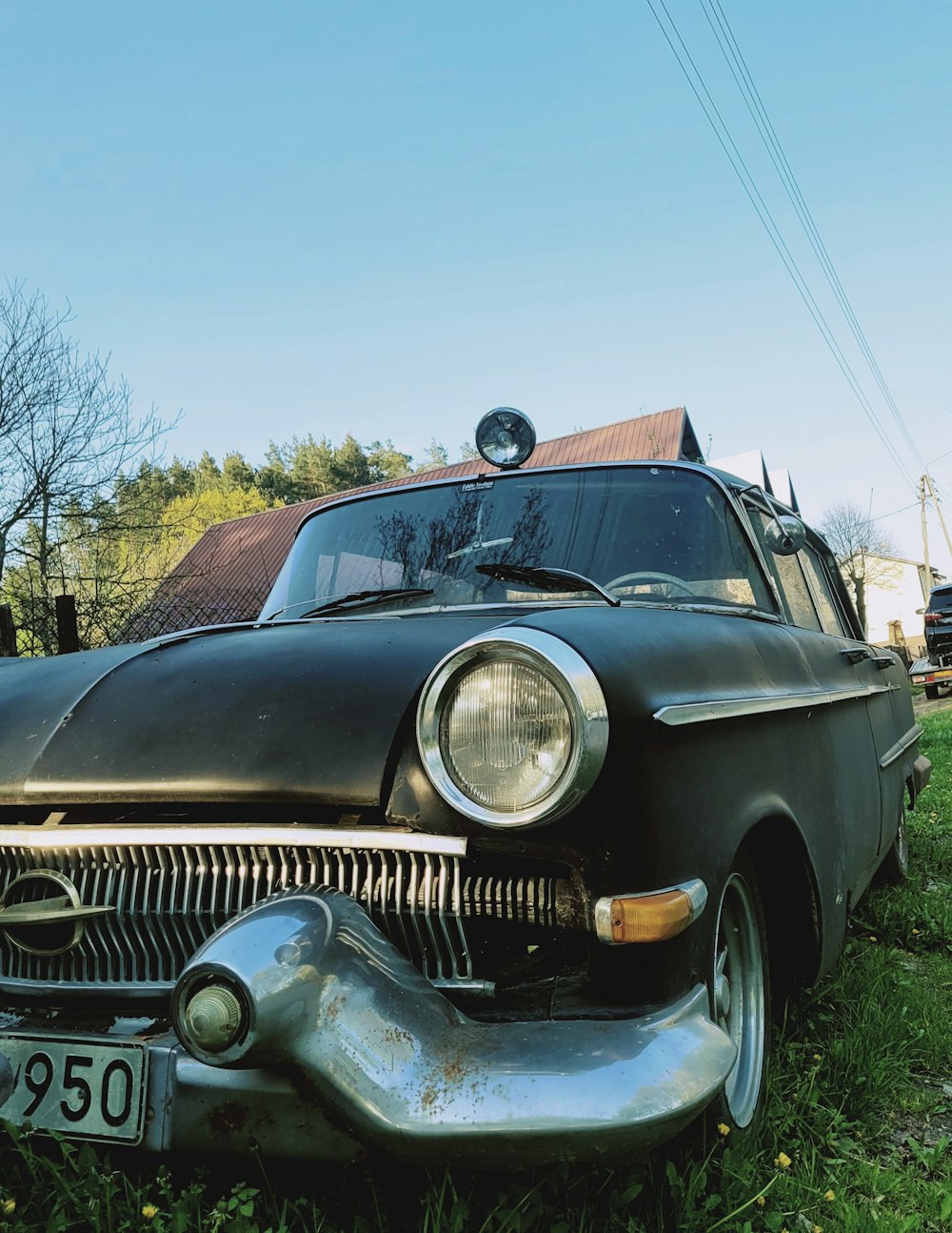 an old black car is parked in the grass