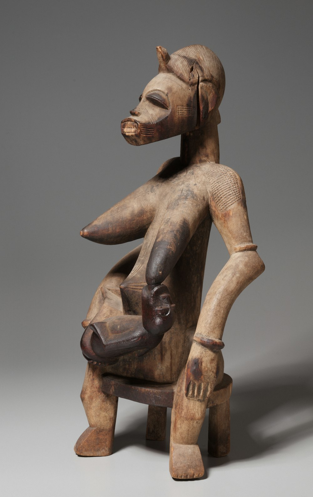 a wooden statue of a person sitting on a chair