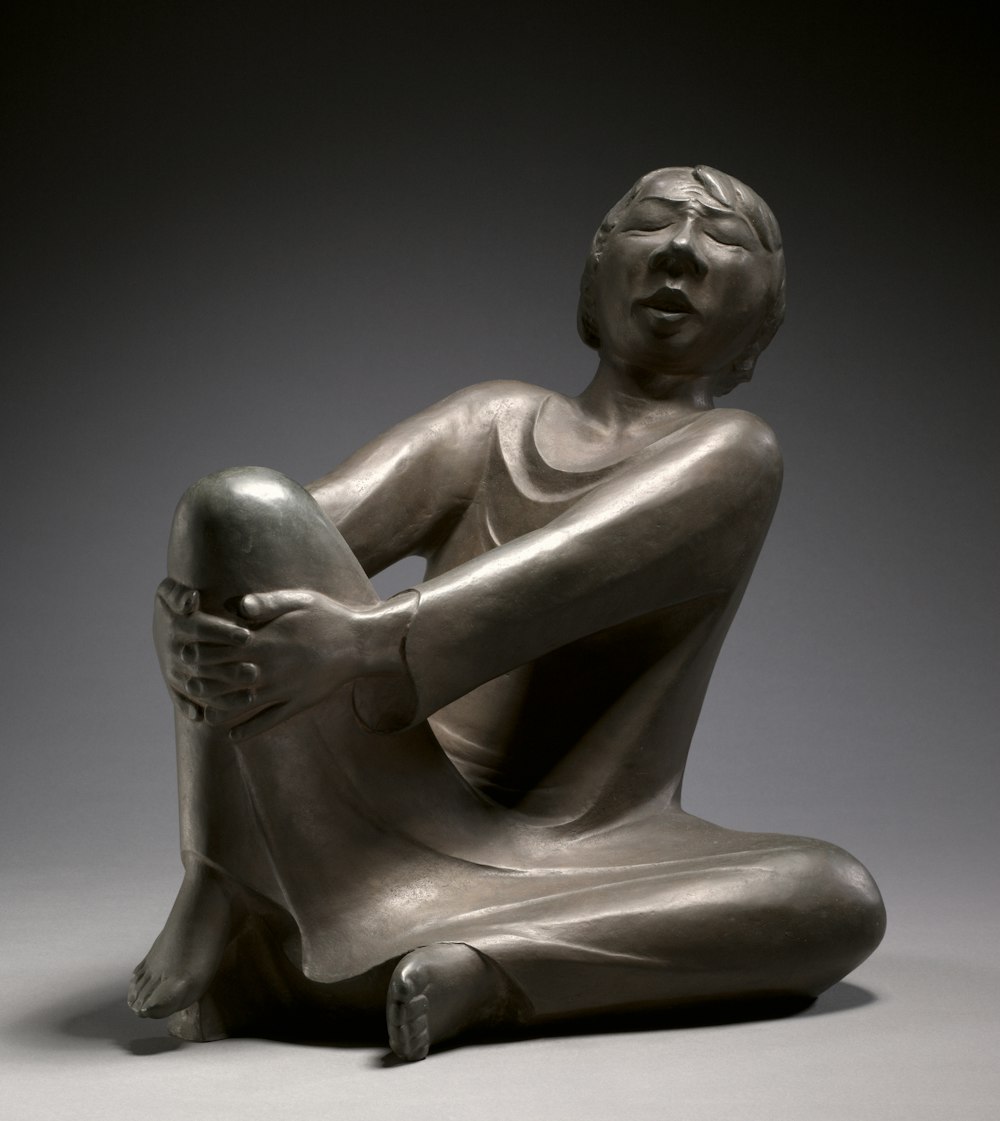 a statue of a person sitting on the ground