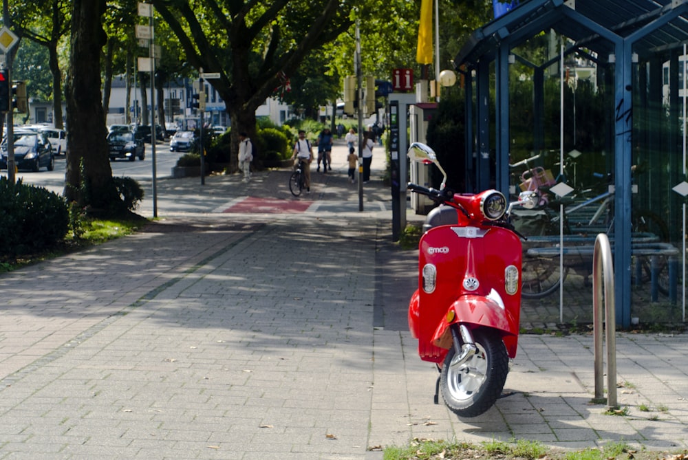 a red scooter parked on the side of a street