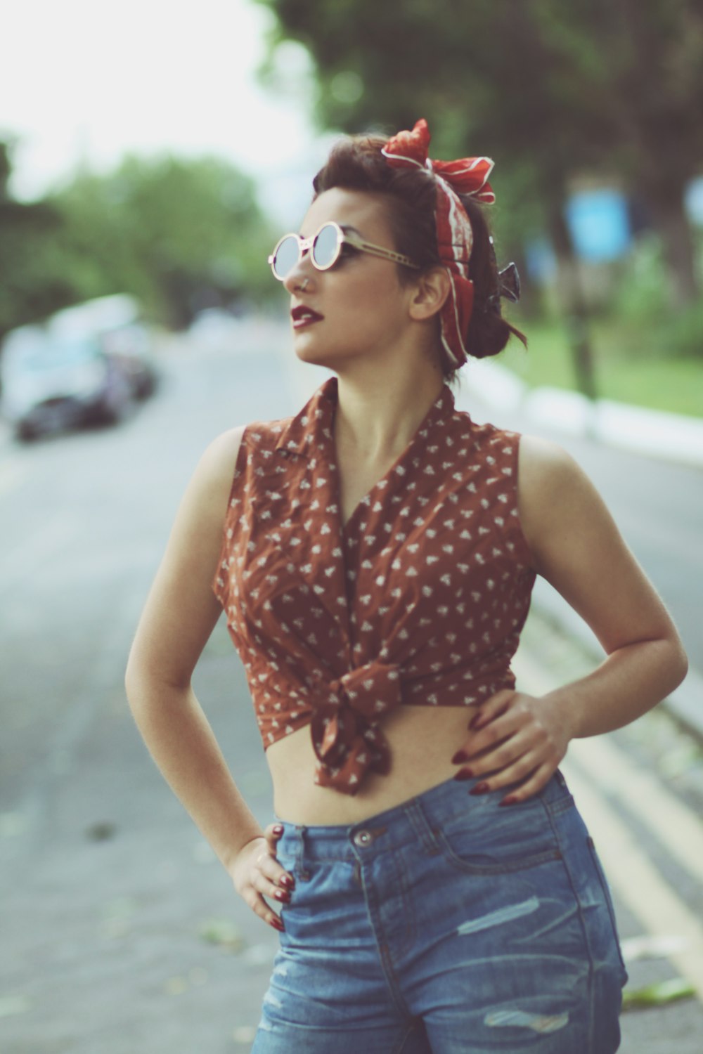 a woman in a polka dot top is standing on the side of the road