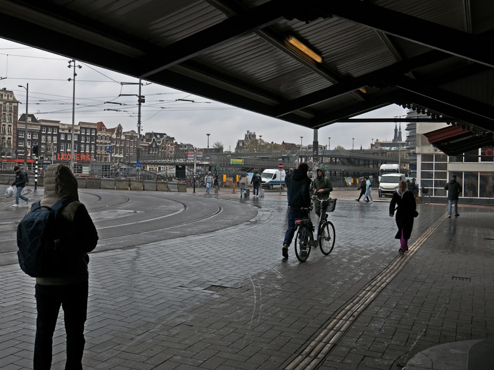 un gruppo di persone che camminano e vanno in bicicletta in una giornata piovosa