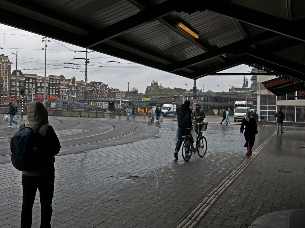 a group of people walking and riding bikes on a rainy day