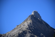 The towering peak of Mount Kilimanjaro against a bright blue sky.