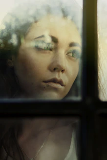 a woman looking out of a window with her eyes closed