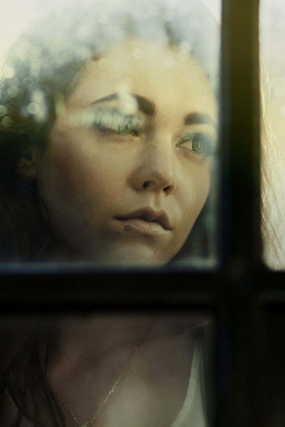 a woman looking out of a window with her eyes closed